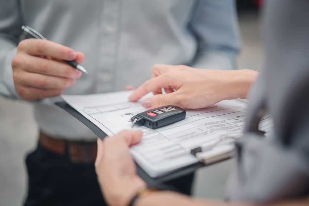 Car Sale Or Rental Concept, Closeup Dealership Manager Signing Car Insurance Document Or Lease Paper Contract. Customer With Car Dealer Agent Making Deal, Sign On Agreement Document Contract In Office