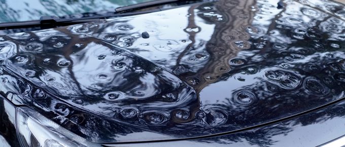 Close up View Of The Hood, Front Pillar, And Part Of The Roof Of A Car Heavily Damaged By Hail. Highlights The Importance Of Covered Parking And Auto Insurance.